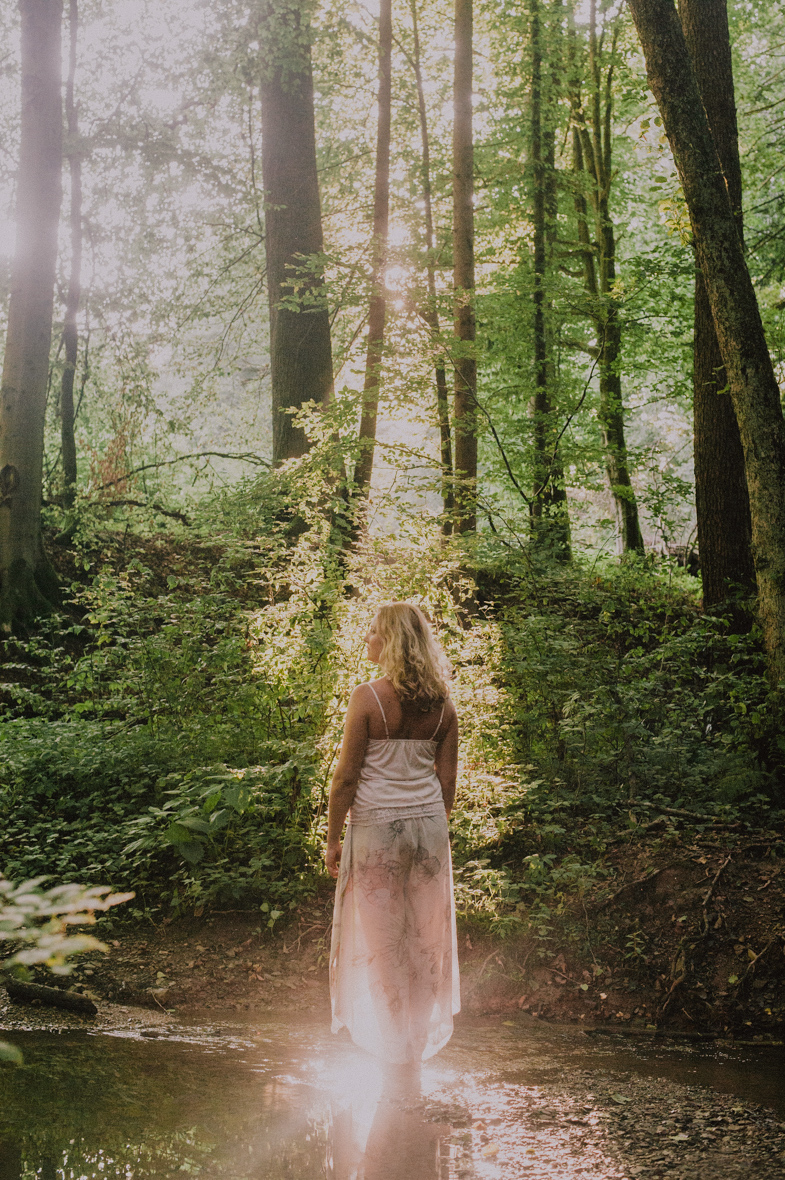Portretna slika ženske v gozdu.